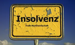 Gelbes, verwittertes Ortsschild mit der Aufschrift "Insolvenz" und "Freie Marktwirtschaft". Es fragt: was ist Insolvenz?