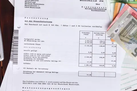 Steuerbescheid mit Geldscheinen. Eine Ratenzahlung ans Finanzamt ist hier nicht direkt ersichtlich, aber das Thema Steuern ist präsent.