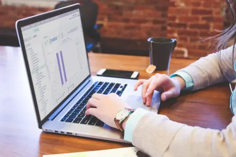 Frau arbeitet am Laptop mit Statistiken, die auf eine effiziente Buchhaltung Gastronomie hindeuten.