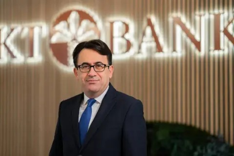 Mann in Anzug vor KT Bank Logo. Positive KT Bank Erfahrung durch professionelles Auftreten.