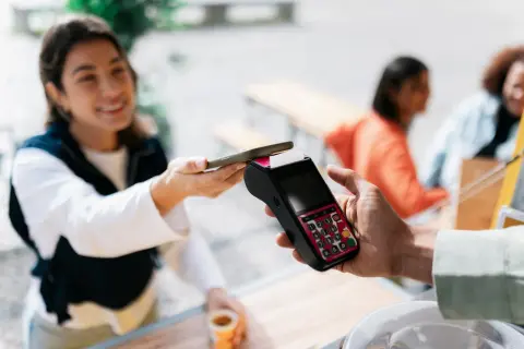 Junge Frau bezahlt kontaktlos mit ihrem Smartphone. Schnelle und einfache mobile payment Transaktion.